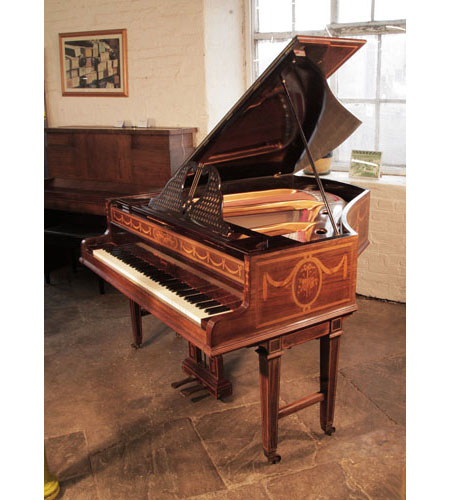 A 1903, Broadwood grand piano with a rosewood case and gate legs.  Cabinet inlaid with swags, bows and panels of musical instruments. Piano has an eighty-five note keyboard and a two-pedal lyre. 