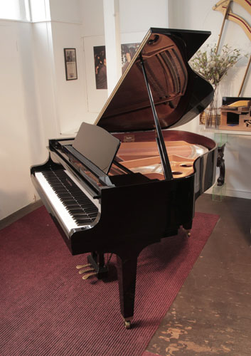 Piano for sale. Reconditioned 1987, Kawai GE-1 baby grand piano for sale with a black case and square, tapered legs. Piano has an eighty-eight note keyboard and a three-pedal lyre. 