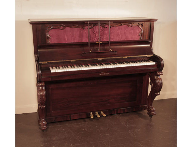 Reconditioned, Victorian upright piano with a rosewood case and carved, cabriole legs. Cabinet features a cut-out front panel backed with silk and bordered with scrolling foliage