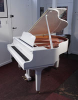 A 2020, Yamaha GB1 baby grand piano for sale with a white, gloss case and square, tapered legs. Piano has an eighty-eight note keyboard and a three-pedal lyre.
