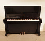 Piano for sale. Reconditioned, 1965, Yamaha U2 upright piano with a black case and polyester finish. Piano has an eighty-eight note keyboard and three pedals. 
