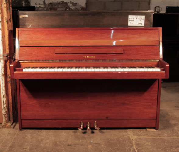 A 1977, Yamaha upright piano with a walnut case and brass fittings. Piano has an eighty-eight note keyboard and three pedals.  