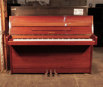 A 1977, Yamaha upright piano with a walnut case and brass fittings 
