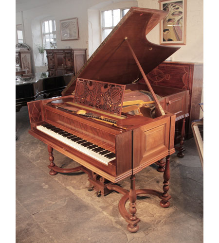 A 1912, Schiedmayer Model 15 grand piano for sale with a harpsichord style mahogany cabinet with bevelled panels and boxwood and satinwood stringing accents. The music desk is in an openwork Arts and Crafts design. The eight baluster legs with bun feet are fixed to a serpentine cross stretcher.