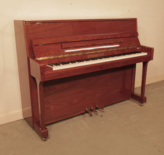 Reconditioned, 2000, Steinhoven  upright piano with a walnut case and polyester finish . Piano has an eighty-eight note keyboard and and three pedals