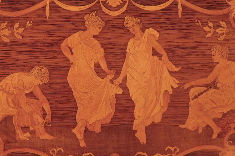 Steinway inlay detail of dancing ladies in billowing dresses, flanked by seated men