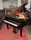 Piano for sale. A 2014, Yamaha GB1 baby grand piano for sale with a black, gloss case and square, tapered legs. Piano has a fitted Disklavier DKC-800 player system. Piano has an eighty-eight note keyboard and a three-pedal lyre.