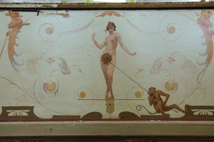 A nude stands on a golden bejeweled goblet, her modesty protected by a fan of peacock feathers held by a nearby monkey